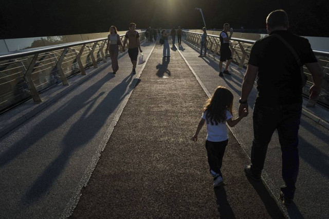 People walk on a pedestrian bridge during the sunset in city center of Kyiv, Ukraine, September 9, 2024.