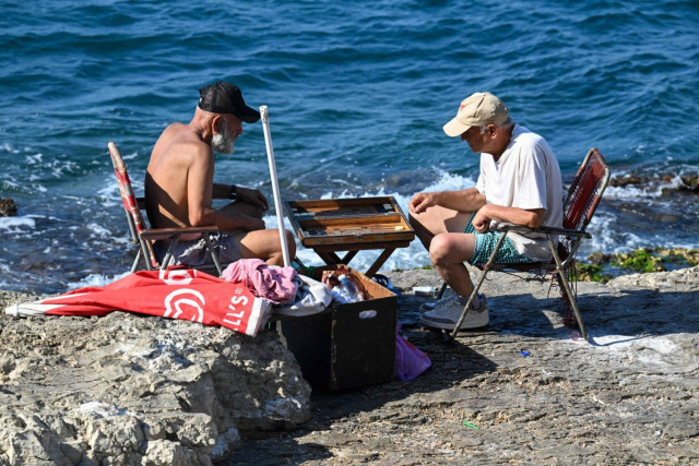People play backgamon on a rock in Beirut's Ain al-Mreisseh seaside promenade on August 2, 2024
